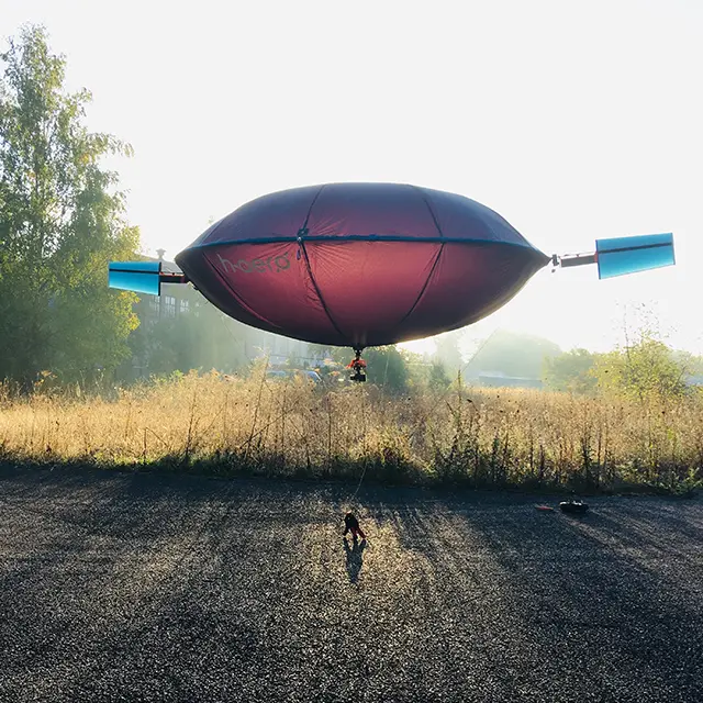 Drohne mit Flugbalon vor einer Wildwiese